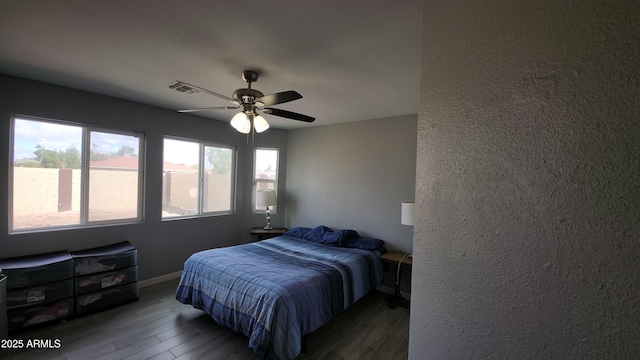 bedroom with visible vents, a ceiling fan, baseboards, and wood finished floors