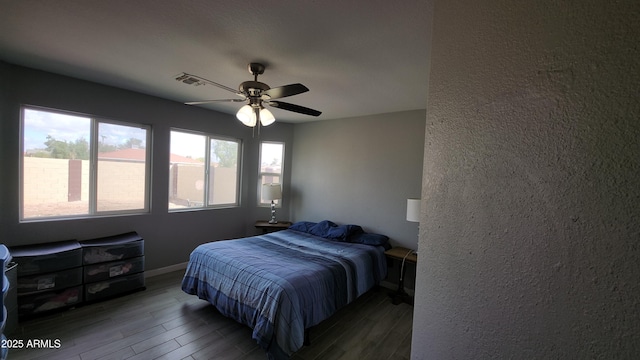 bedroom featuring visible vents, ceiling fan, baseboards, and wood finished floors