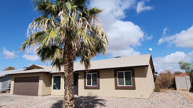 ranch-style house featuring concrete driveway, an attached garage, roof with shingles, and stucco siding