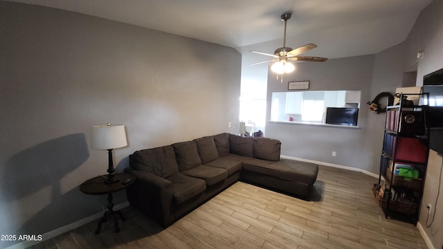 living room featuring vaulted ceiling, wood finished floors, baseboards, and ceiling fan