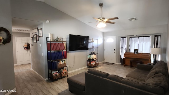 living room with a ceiling fan, visible vents, baseboards, light wood-style flooring, and vaulted ceiling