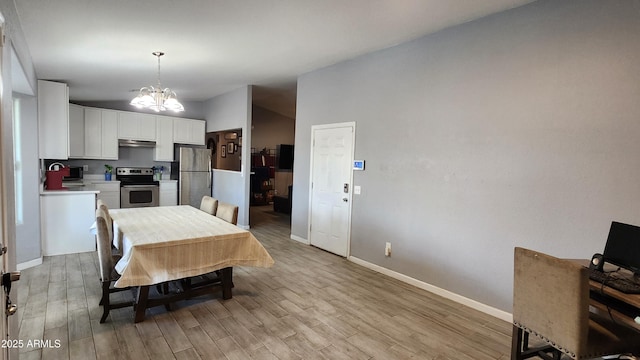 dining area featuring light wood-type flooring, baseboards, lofted ceiling, and a chandelier