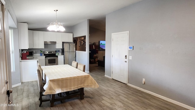 kitchen with under cabinet range hood, light wood-style flooring, an inviting chandelier, white cabinets, and stainless steel appliances