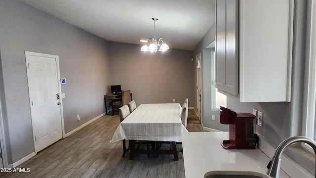 dining area with a notable chandelier, wood finished floors, and baseboards