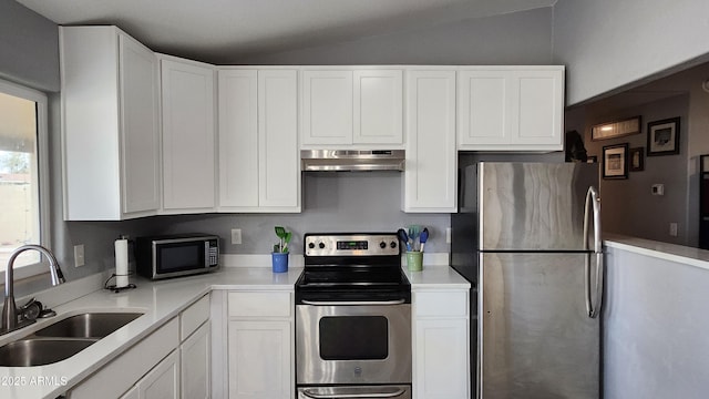 kitchen with under cabinet range hood, a sink, white cabinetry, stainless steel appliances, and vaulted ceiling