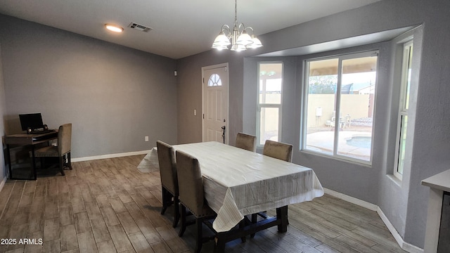 dining space featuring an inviting chandelier, wood finished floors, visible vents, and baseboards