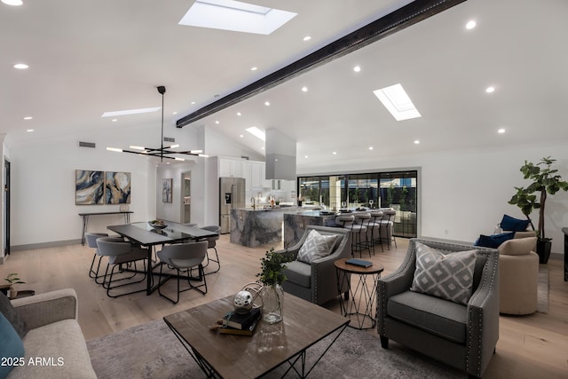 living room with crown molding, vaulted ceiling with skylight, a notable chandelier, and light wood-type flooring