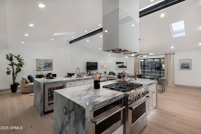 kitchen featuring light stone countertops, appliances with stainless steel finishes, a large island, white cabinetry, and beverage cooler