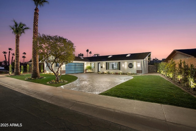 ranch-style house featuring a garage and a lawn