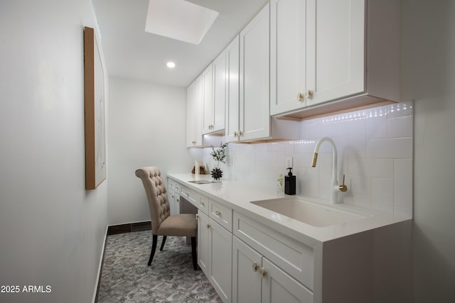 interior space with white cabinets, sink, light stone countertops, and backsplash