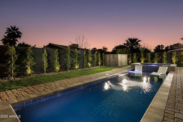 pool at dusk featuring an in ground hot tub