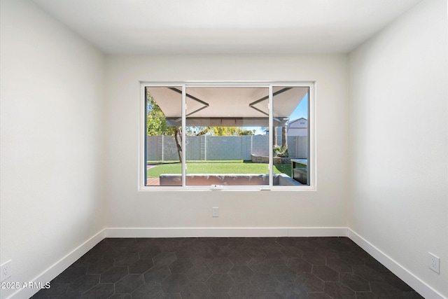 empty room featuring dark tile patterned flooring and a wealth of natural light