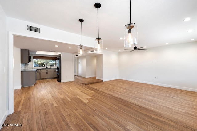 unfurnished living room featuring ceiling fan and light wood-type flooring