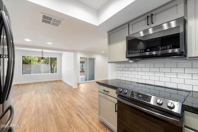 kitchen featuring hanging light fixtures, light hardwood / wood-style floors, gray cabinets, backsplash, and appliances with stainless steel finishes