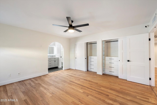 unfurnished bedroom with multiple closets, ceiling fan, light hardwood / wood-style floors, and connected bathroom