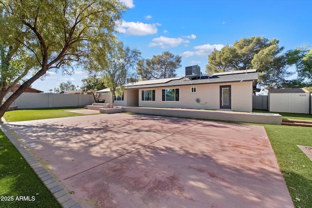 rear view of house with a patio, a yard, central air condition unit, solar panels, and a shed