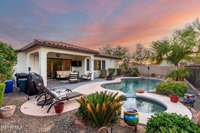 12798 W Dove Wing Way, Peoria, AZ 85383 - pool at dusk featuring outdoor lounge area, an in-ground hot tub, a patio, and a fenced backyard