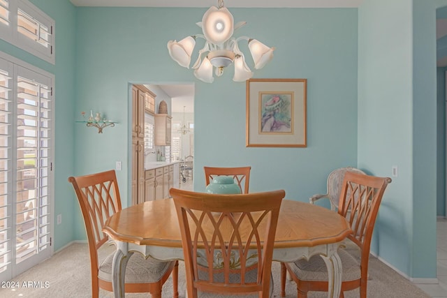 dining area featuring light colored carpet and an inviting chandelier