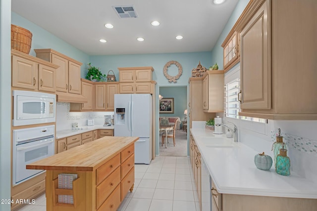 kitchen with light brown cabinets, sink, a center island, wood counters, and white appliances