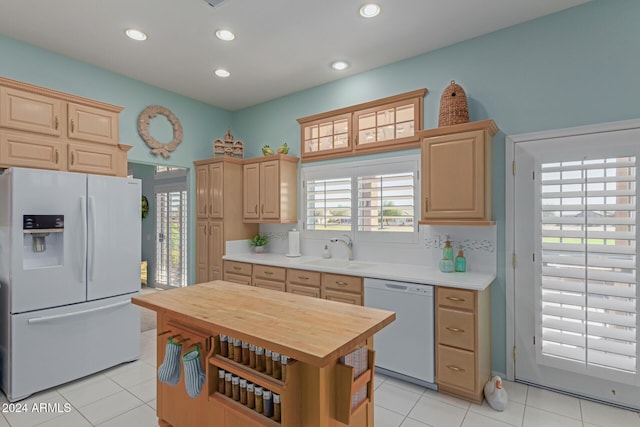 kitchen featuring light brown cabinetry, light tile patterned floors, white appliances, and sink