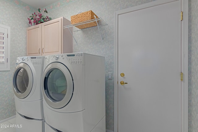 laundry room featuring separate washer and dryer and cabinets