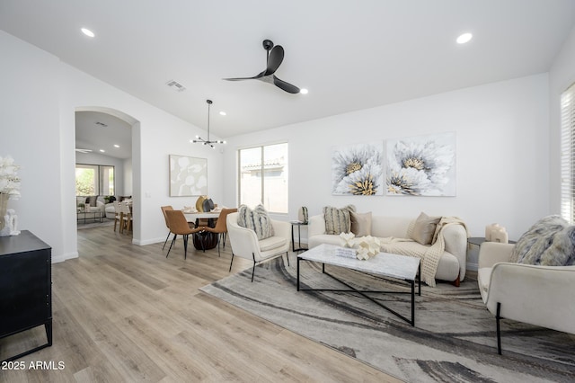 living room with vaulted ceiling, ceiling fan, and light wood-type flooring