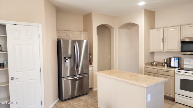 kitchen featuring cream cabinetry, light tile patterned floors, appliances with stainless steel finishes, and a center island