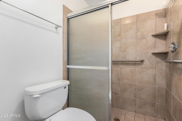 bathroom featuring a shower with door and toilet