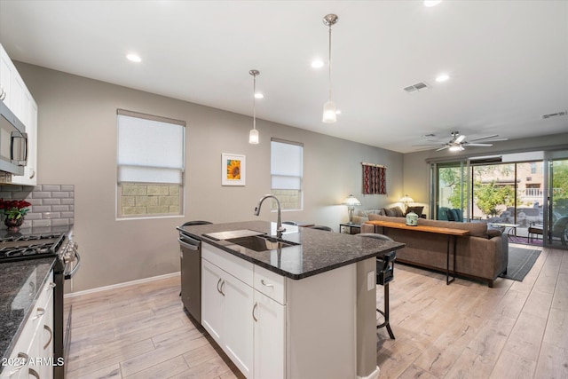 kitchen featuring white cabinets, sink, appliances with stainless steel finishes, and an island with sink