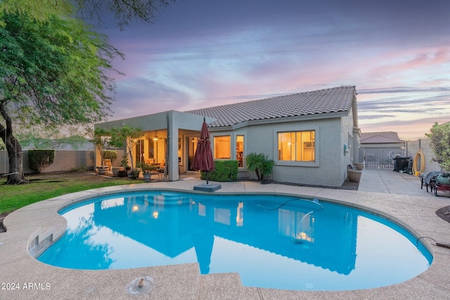 pool at dusk with a patio area