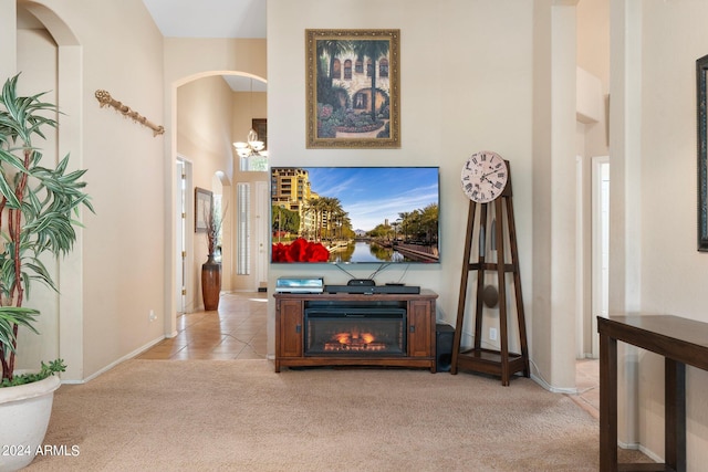 corridor featuring carpet, a high ceiling, a chandelier, tile patterned flooring, and baseboards