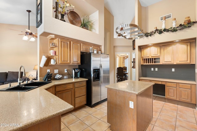 kitchen with a sink, a kitchen island, open shelves, built in desk, and stainless steel fridge