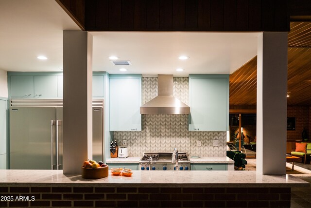 712 W Vernon Ave, Phoenix, AZ 85007 - kitchen with light stone countertops, visible vents, built in fridge, decorative backsplash, and wall chimney range hood
