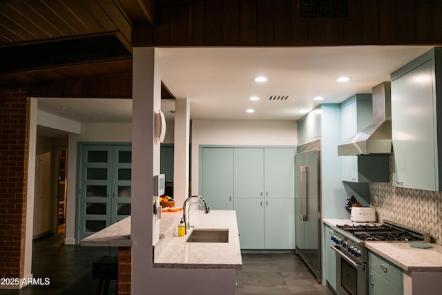 712 W Vernon Ave, Phoenix, AZ 85007 - kitchen featuring premium appliances, light stone counters, a sink, decorative backsplash, and wall chimney exhaust hood