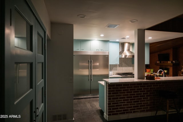 712 W Vernon Ave, Phoenix, AZ 85007 - kitchen featuring wall chimney range hood, visible vents, white cabinets, light stone countertops, and built in fridge