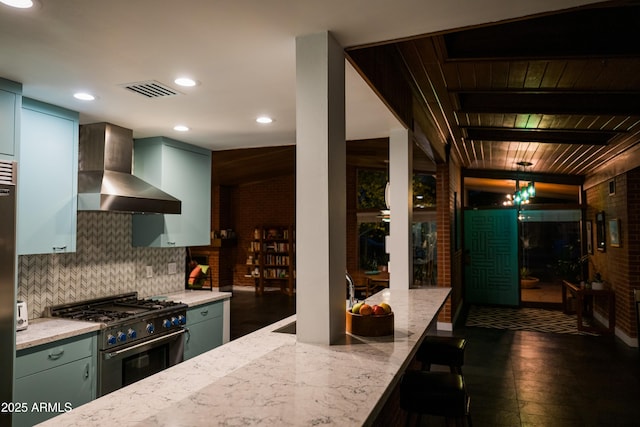 712 W Vernon Ave, Phoenix, AZ 85007 - kitchen featuring backsplash, light stone counters, wall chimney exhaust hood, and stainless steel range
