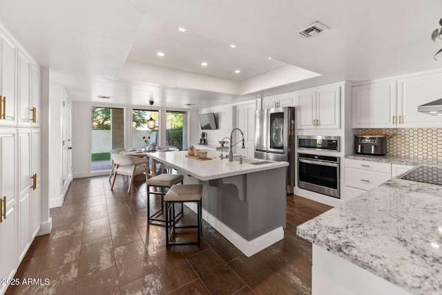 4392 W Charro Ln, Yuma, AZ 85365 - kitchen featuring appliances with stainless steel finishes, a raised ceiling, a sink, tasteful backsplash, and white cabinets
