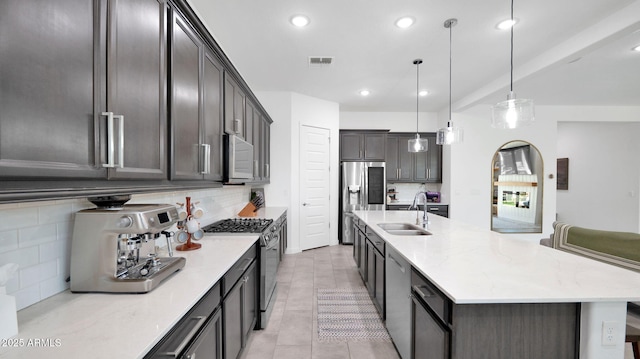 kitchen with pendant lighting, tasteful backsplash, sink, light tile patterned floors, and stainless steel appliances