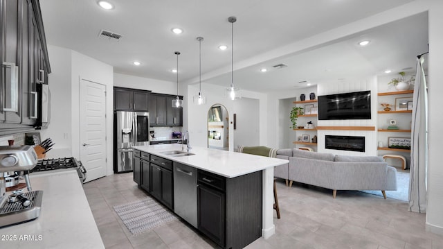 kitchen with pendant lighting, sink, a kitchen breakfast bar, stainless steel appliances, and an island with sink