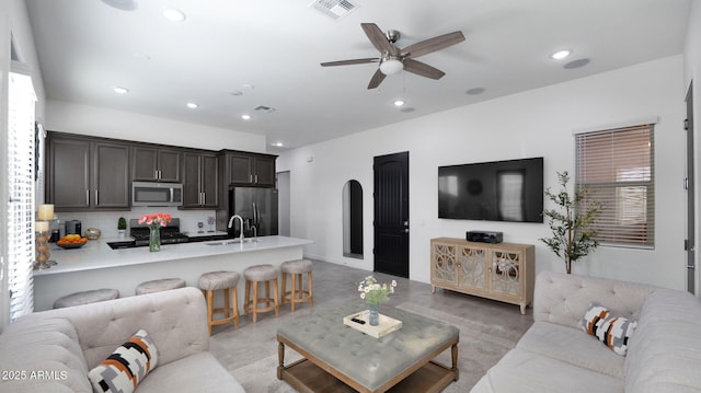 living room with ceiling fan, a healthy amount of sunlight, and sink