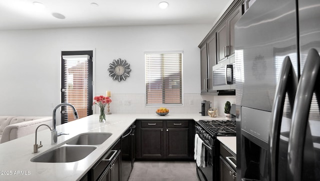 kitchen featuring dark brown cabinetry, sink, kitchen peninsula, stainless steel appliances, and decorative backsplash