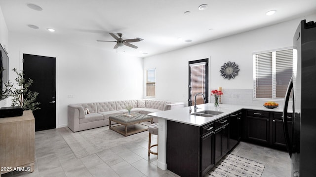 kitchen featuring black refrigerator, sink, a kitchen bar, ceiling fan, and kitchen peninsula