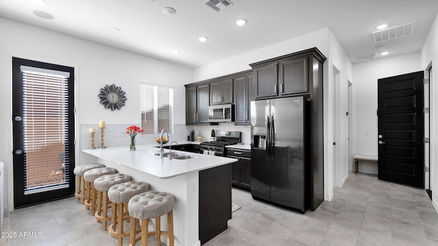 kitchen with sink, a breakfast bar, appliances with stainless steel finishes, tasteful backsplash, and kitchen peninsula