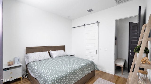 bedroom with light hardwood / wood-style floors and a barn door