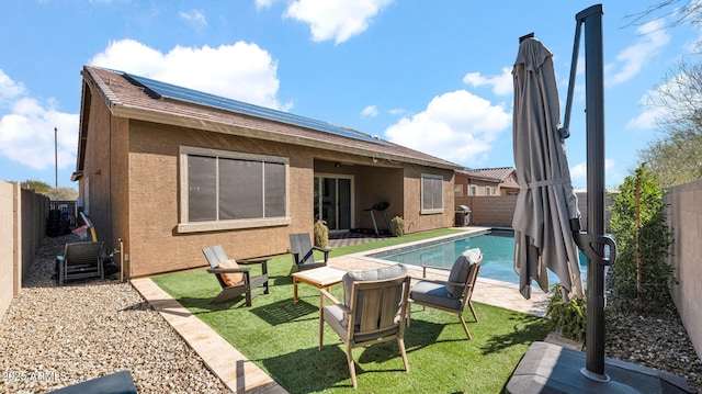 rear view of house featuring a fenced in pool, a yard, a patio, and solar panels