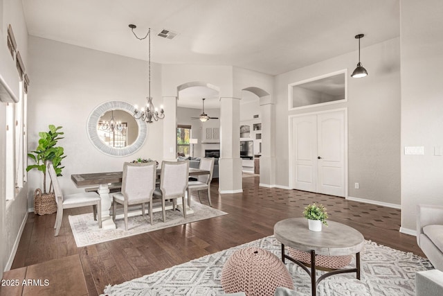 living room with dark hardwood / wood-style flooring and ceiling fan with notable chandelier