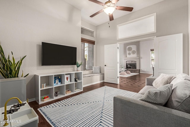 living room with a high ceiling, dark hardwood / wood-style floors, and ceiling fan