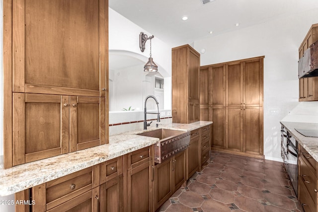 kitchen with sink, black electric stovetop, light stone countertops, dark tile patterned flooring, and decorative light fixtures