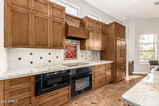 kitchen with premium range hood, light stone countertops, decorative backsplash, and black appliances