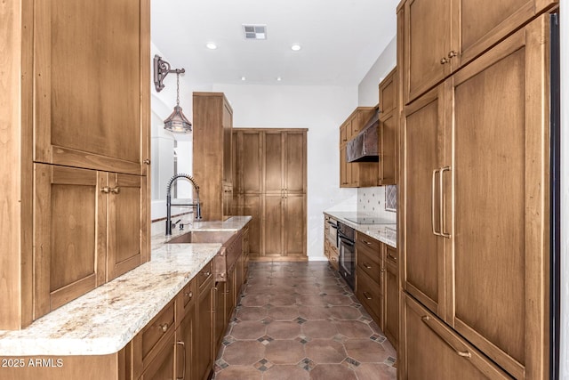 kitchen with pendant lighting, sink, dark tile patterned floors, light stone counters, and black appliances